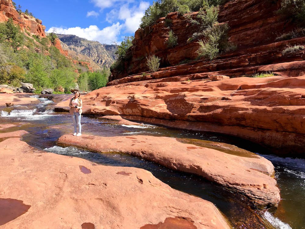 addie standing on a rock in the middle of the river at slide rock state park