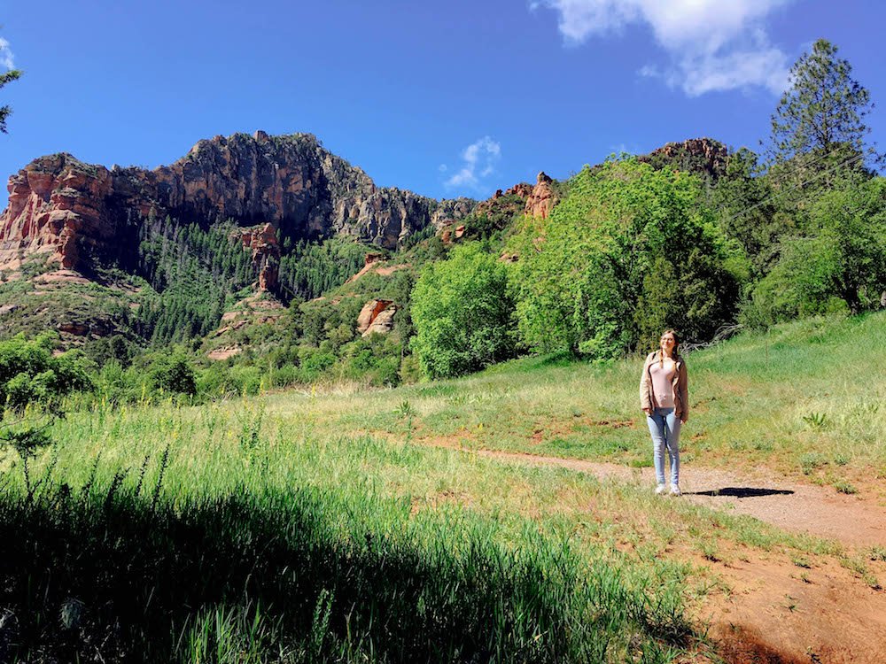 addie standing on a dirt trail in front of red rocks