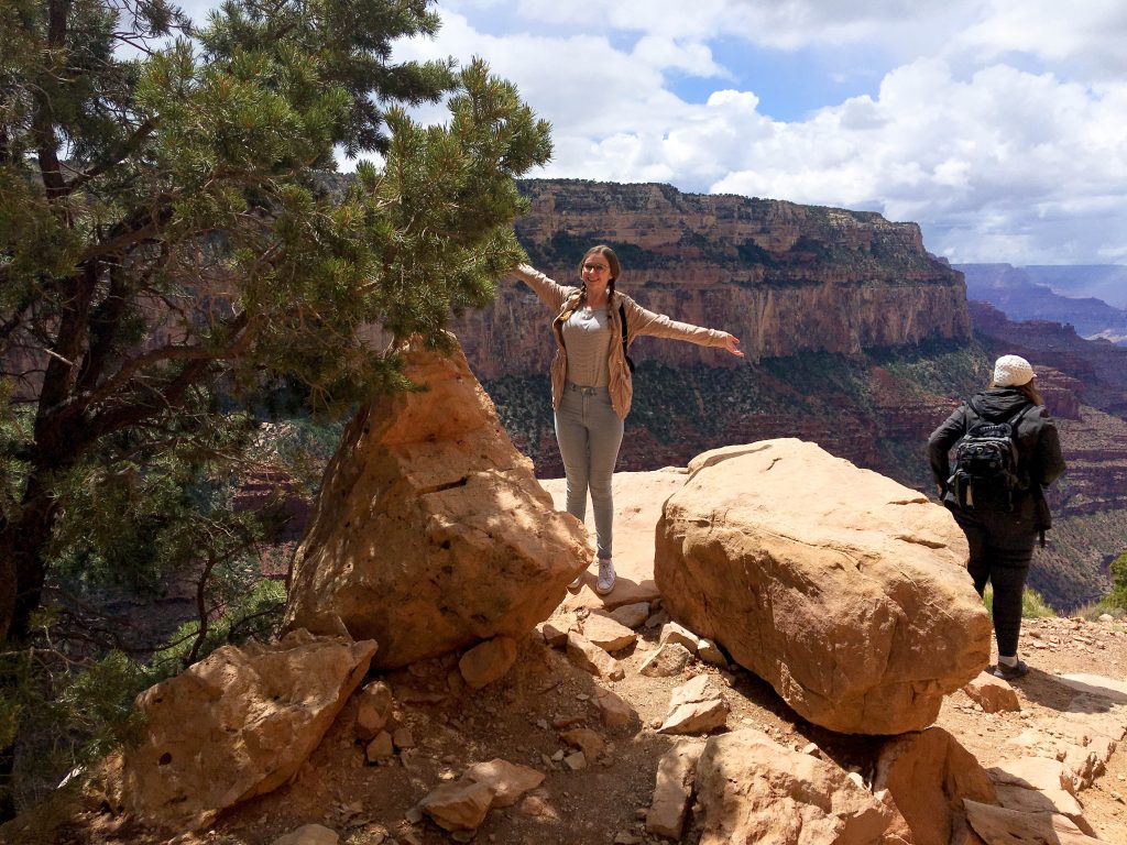 Addie standing with her arms out on the rim of the Grand Canyon