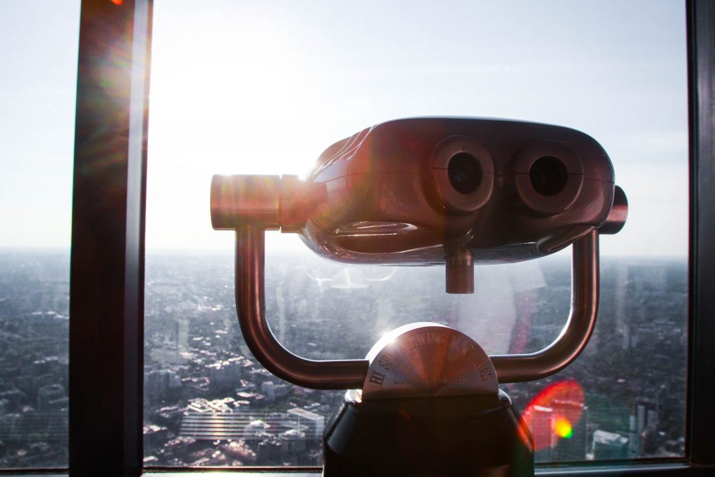 A CN Tower Telescope with a sun flare behind it