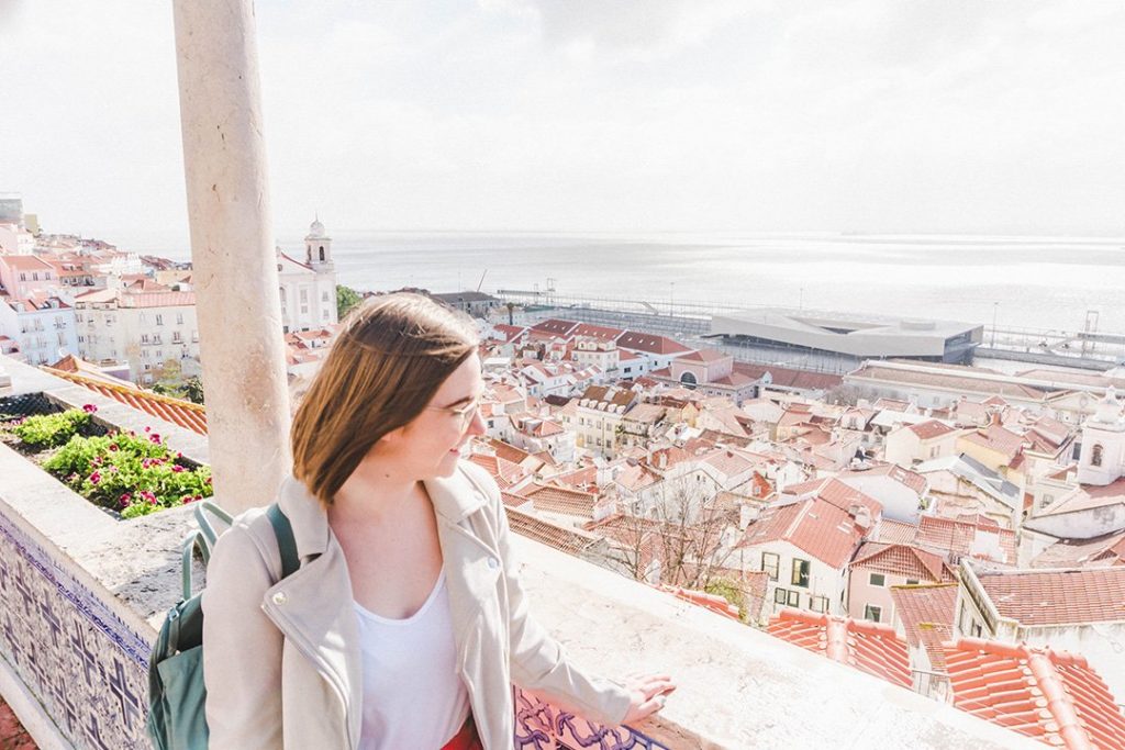Addie staring out across Lisbon from a viewpoint. Lisbon is one of the best solo female travel destinations!