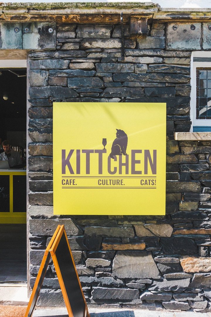 A yellow sign for Kittchen, the only cat cafe in the world that doesn't charge an admission fee, found in the tiny town of Hawkshead, Lake District, UK