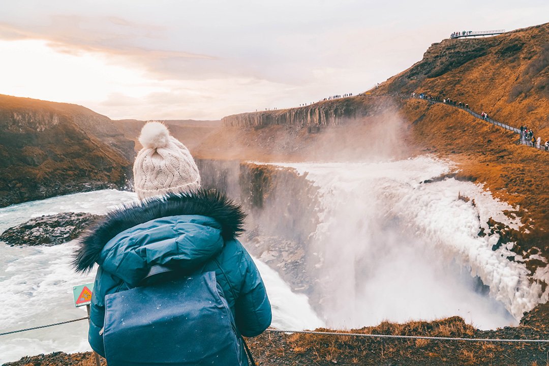 Addie staring out at Gulfoss lit up during Golden Hour