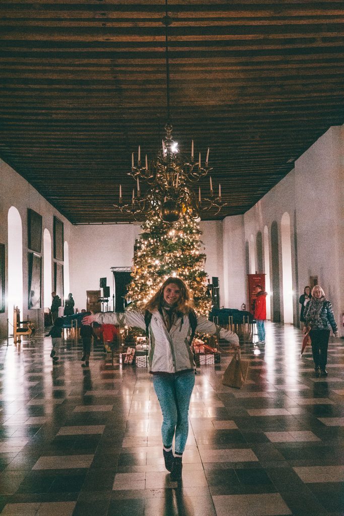 Megan standing in front of the Christmas tree in the Kronborg Castle ballroom