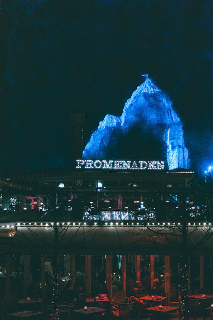 A fake mountain rising up in the background of a lit up scene at Tivoli Gardens Christmas Market