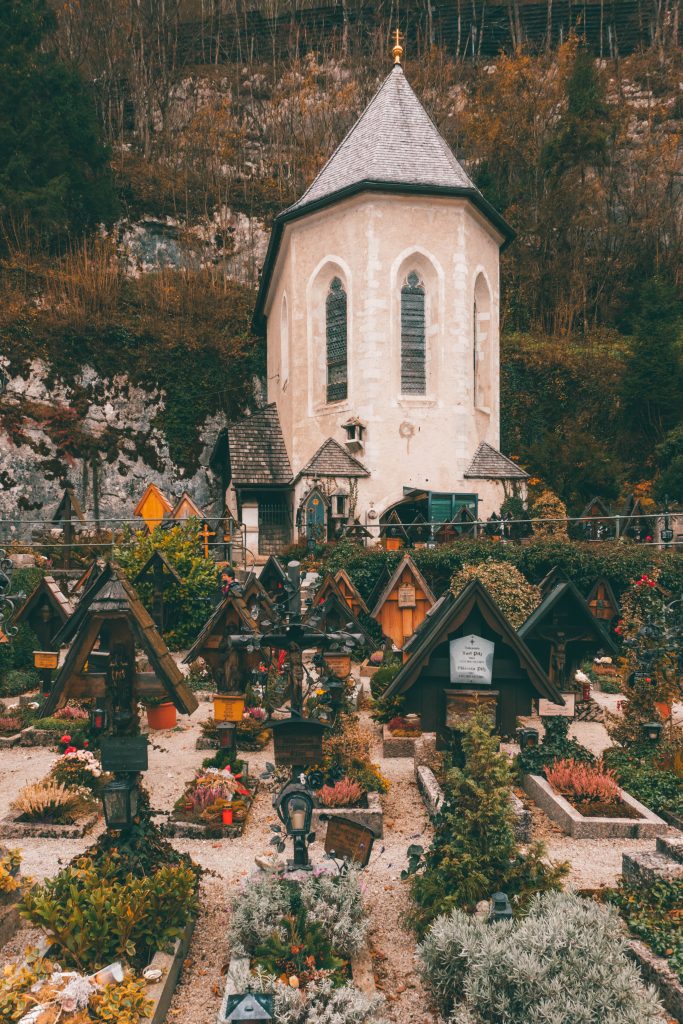 A small graveyard with wooden crosses marking the grave in front of a small church in Hallstatt, Austria