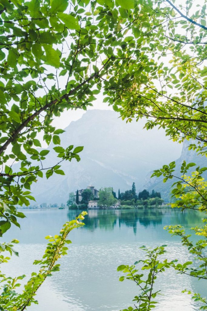 Toblino castle through the green leaves of a bush