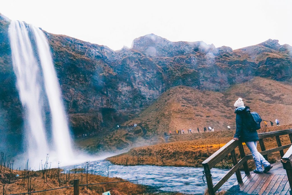 Addie standing on a bridge by Seljalandsfoss waterfall in iceland in December
