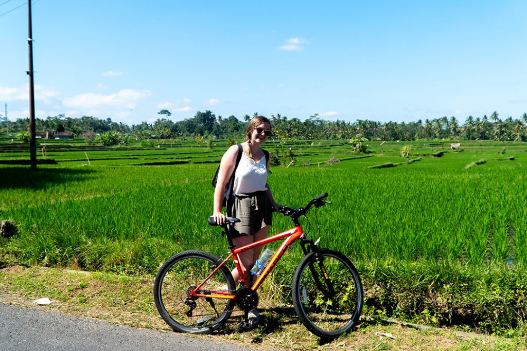 Addie with a bike in front of Ubud rice fields 