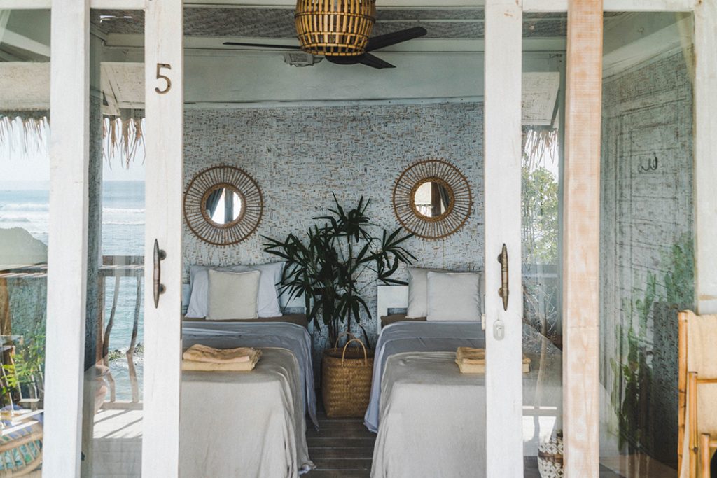 Sliding glass doors opening to two white-blanketed twin beds - the most gorgeous accommodation at a bali surf camp ever!