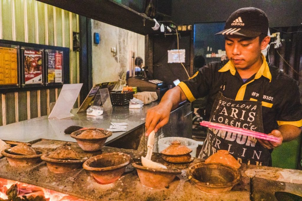 A man cooking Martabk Manis in small clay pots