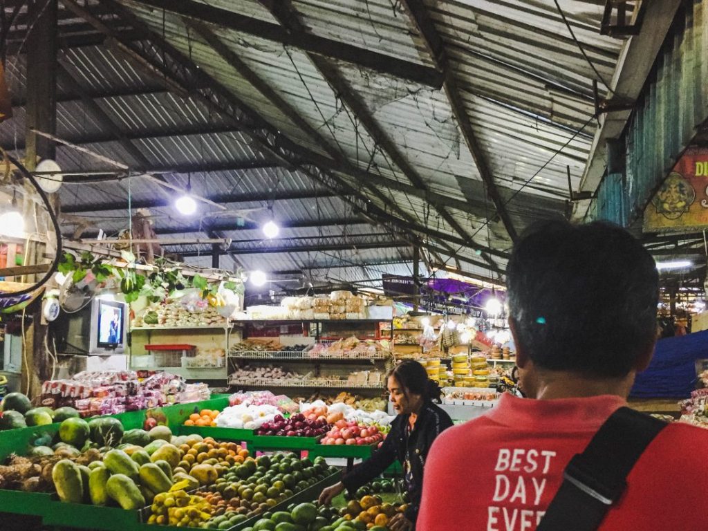 Urban Adventures guide walking through a local market during a Total Bali Food tour