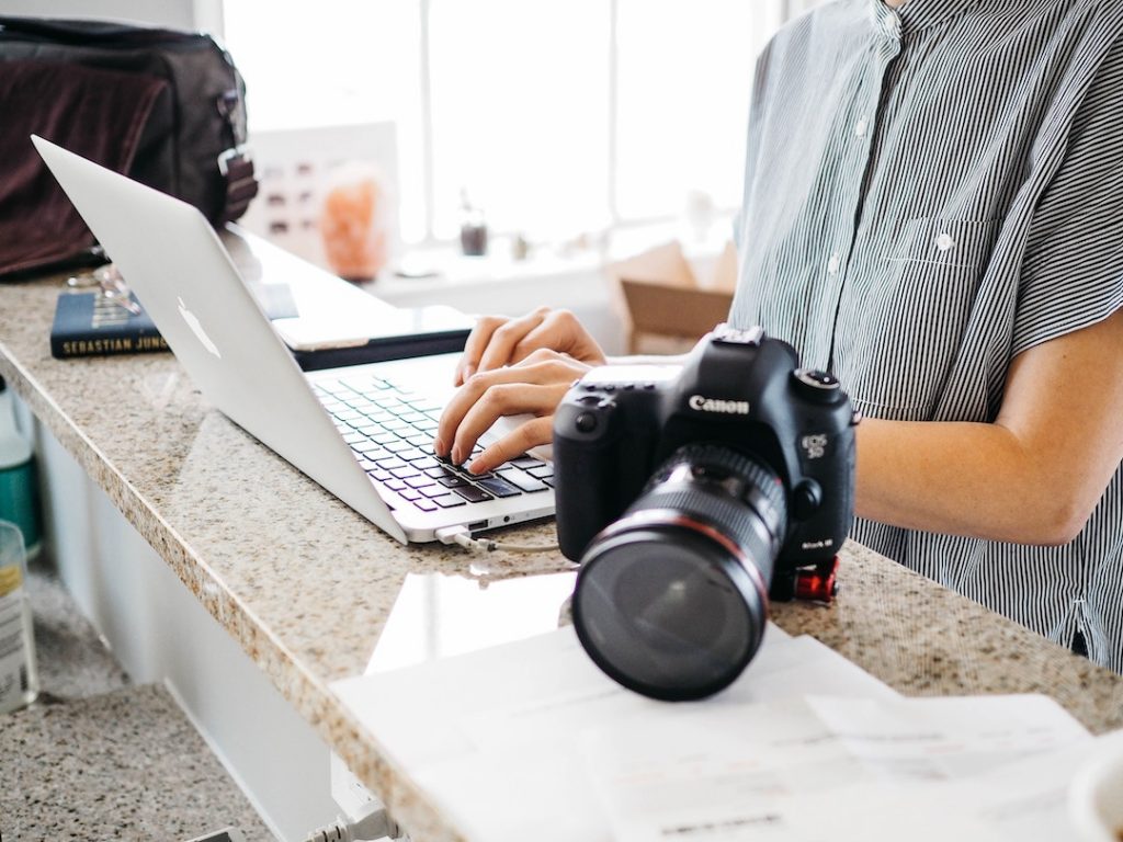 a person sitting at a counter with a laptop and camera