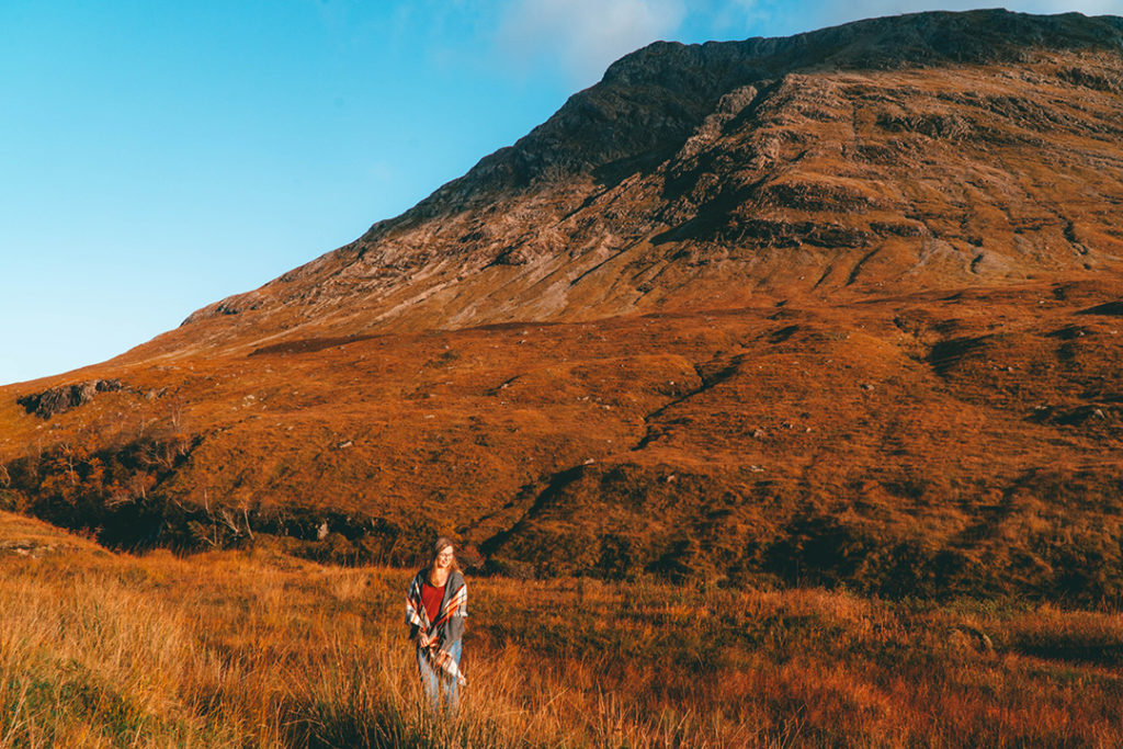 Addie standing in the grass in front of a mountain in Glen Etive