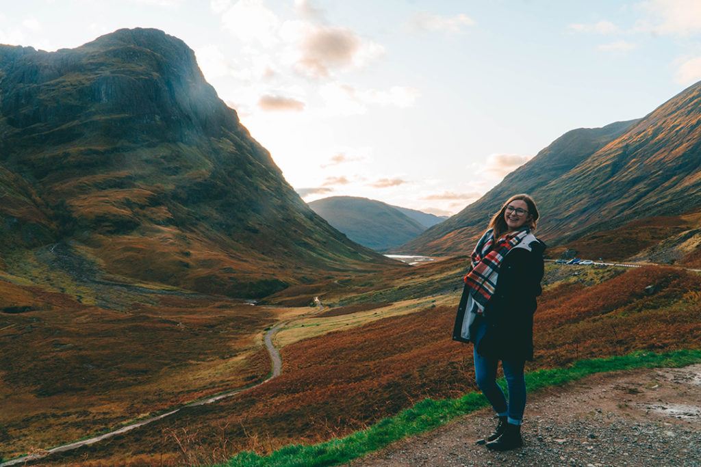 Addie standing in front of Glencoe, one of the best solo female travel destinations