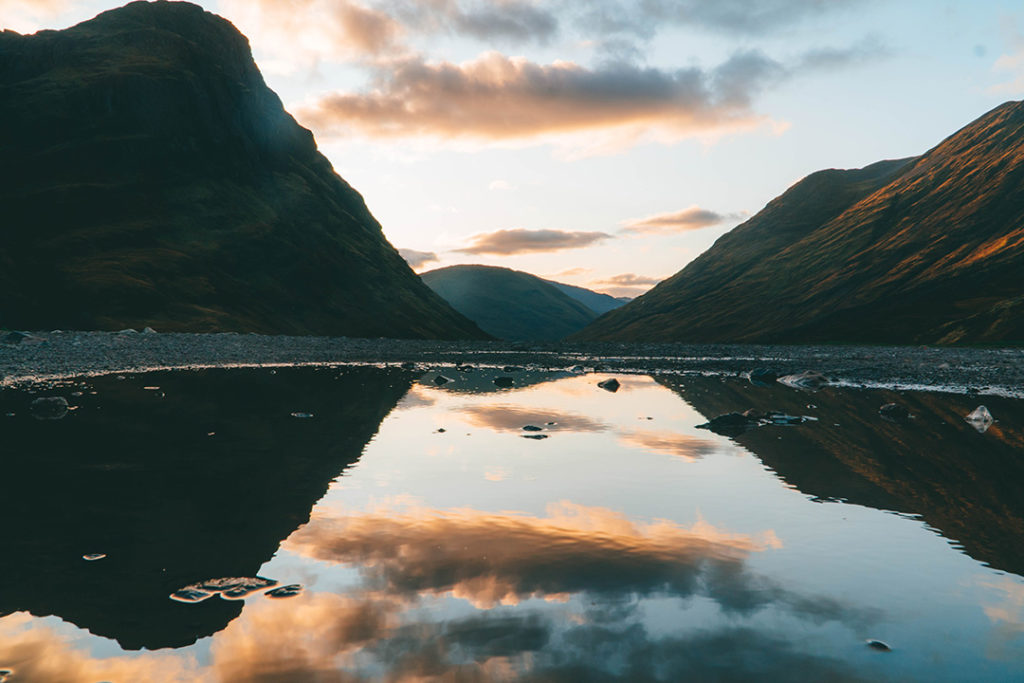 The mountains of glencoe reflected in a puddle. Glencoe is a must-see on any Highlands and Isle of Skye tour from Edinburgh