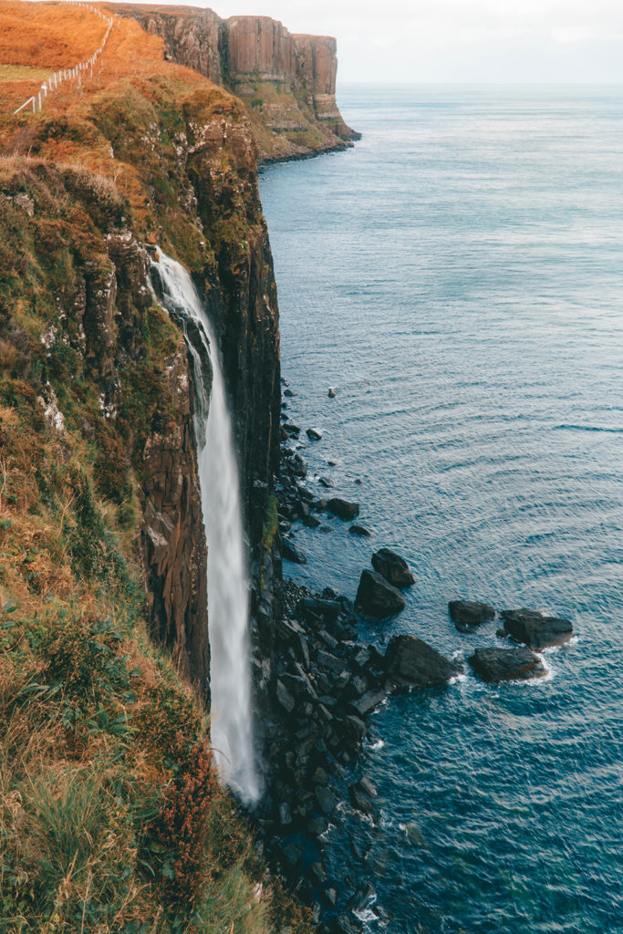 a waterfall cascading down a cliff - kilt rock, a stop on the Rabbie's isle of skye tour from Edinburgh