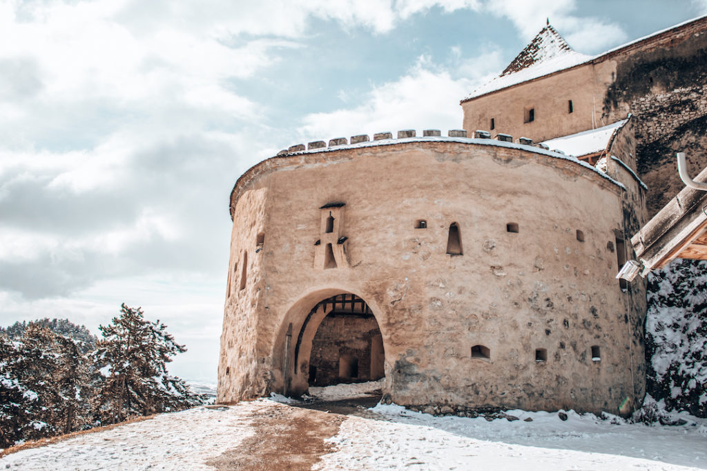 a castle dusted in snow in Romania, one of the best places to visit in Europe in winter