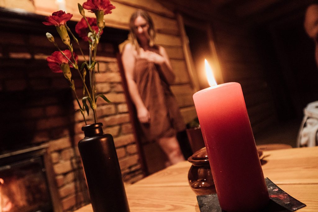 addie standing in a towel, blurred out with a candle and vase of flowers on the table in front of her