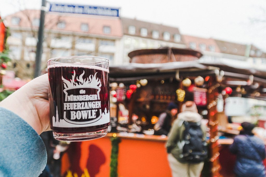 a hand holding up a glass full of punch in front of the largest punch bowl in the world