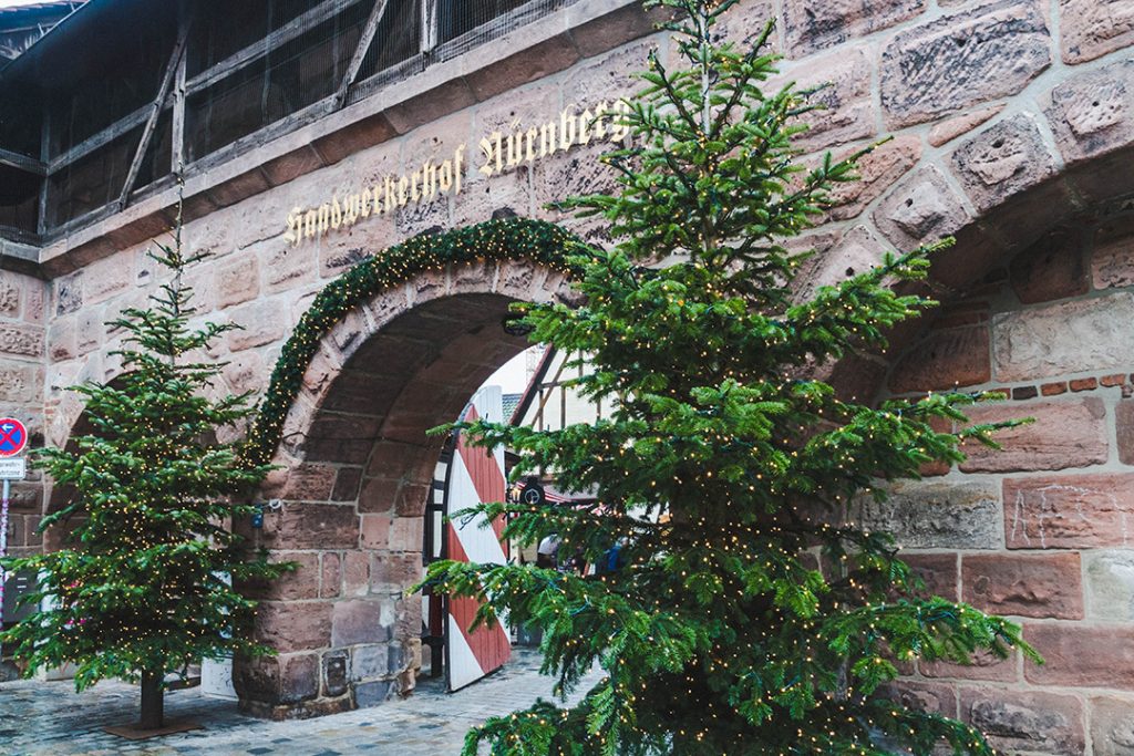 the entrance to the handwerkerhof flanked by christmas trees in nuremberg, germany