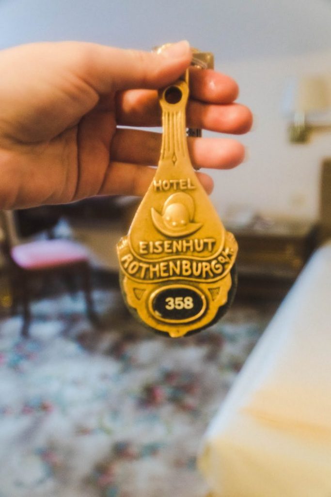 A hand holding up a gilded key for the Hotel Eisenhut