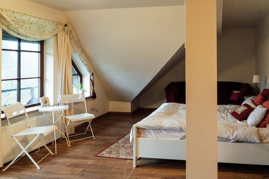 a white bed and white table and chairs in a room at karlamuiza manor hotel