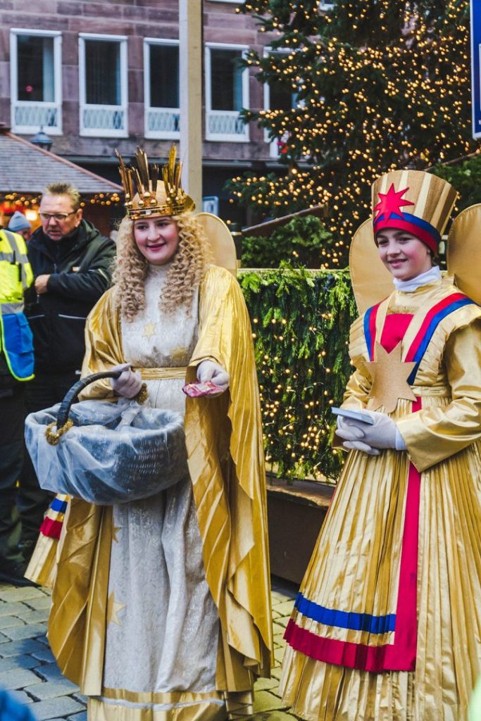 the Nuremberg Christkind and a Rauschgoldengel handing out treats to kids at the Nuremberg Christmas Market