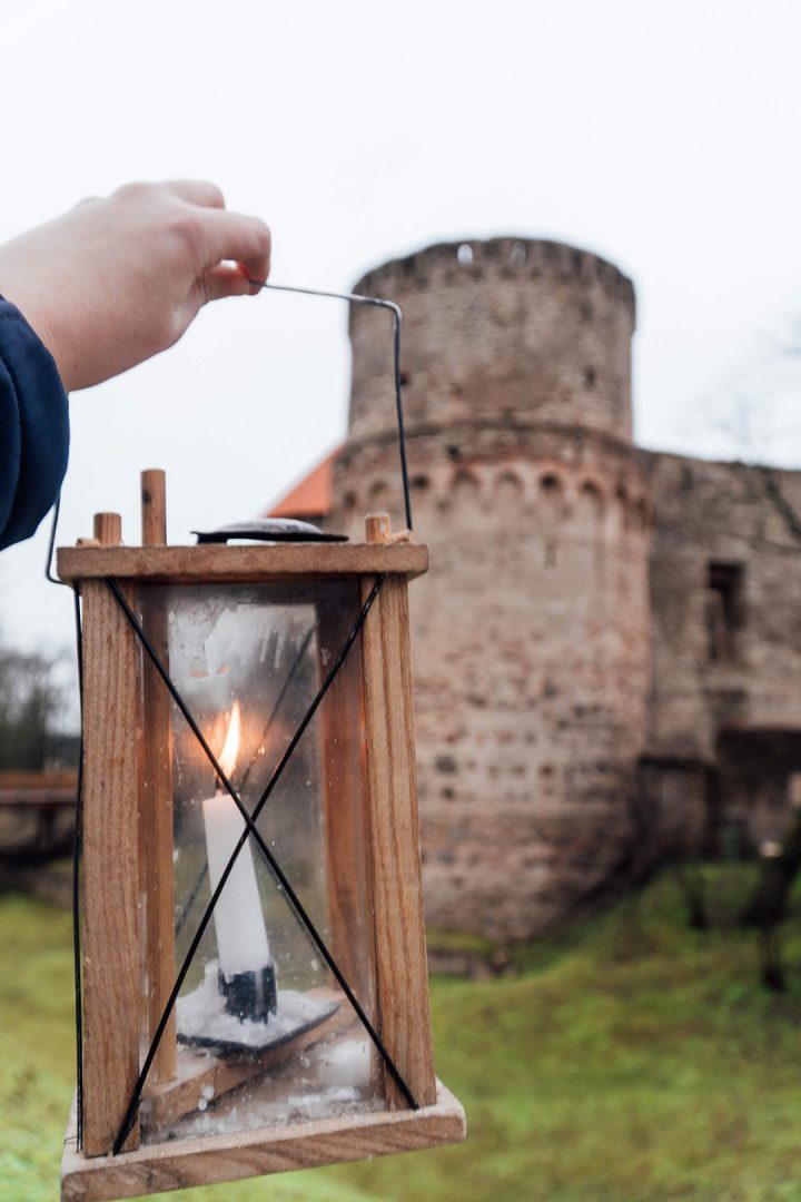 a hand holding up an old timey lamp in front of a castle