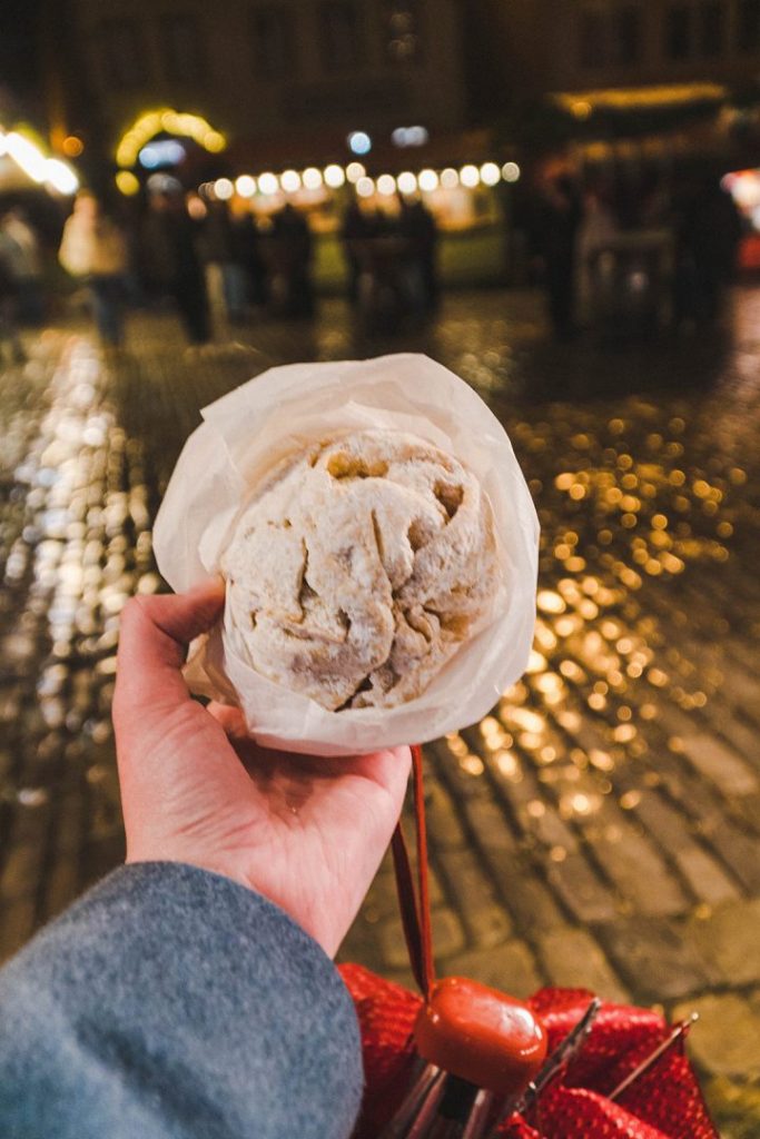 A hand holding up a rolled up ball of pie dough covered in powdered sugar