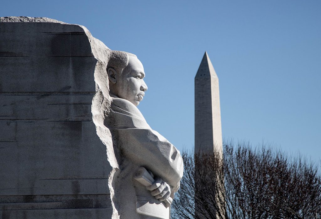 The imposing statue of Martin Luther King Jr, carved out of a rock, with the Washington Monument in the background