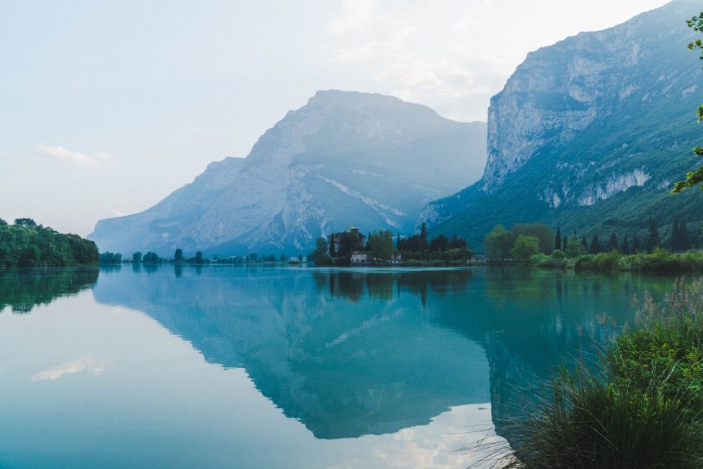 Toblino Castle across a lake and in front of a mountain at dusk