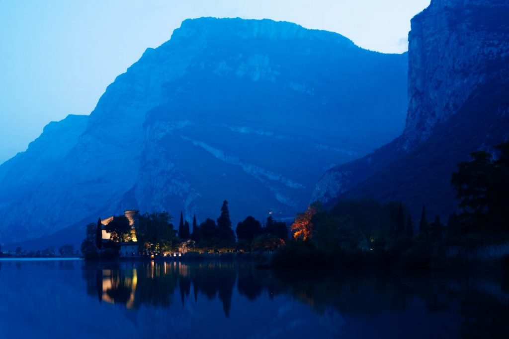 Toblino castle lit up at night across the lake