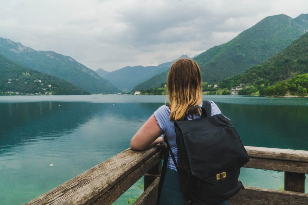 Addie standing on a dock looking out at the lake and mountains of Valle di Ledro, Italy