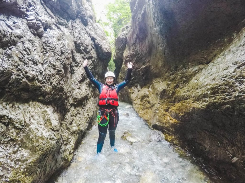 Addie standing with her hands over her head in a small crevice of a canyon