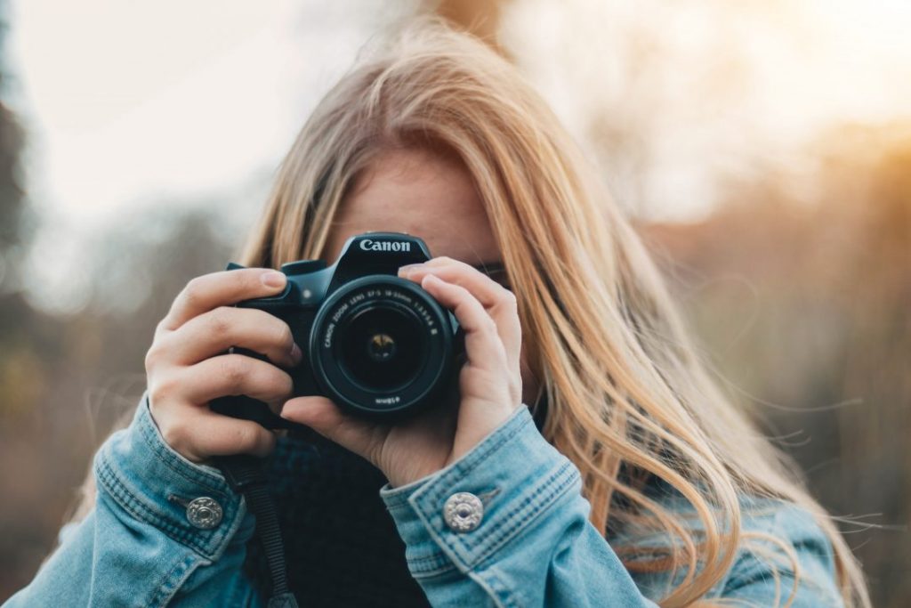 A blonde girl holding a camera up to her eye
