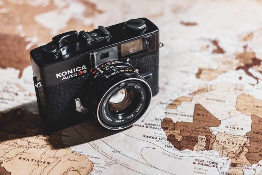 An old Konica camera on a map - how to choose the best camera for travel photography