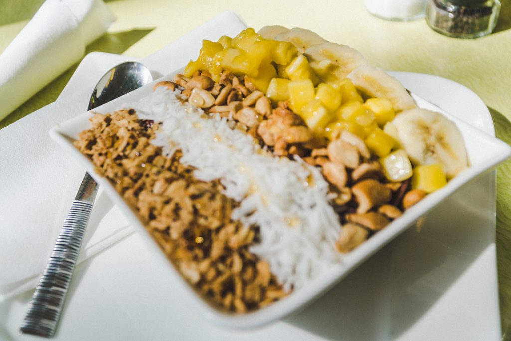a delicious smoothie bowl with layers of nuts, fruit, and coconut