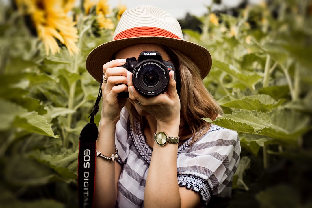 a woman holding a camera in a field of sunflowers