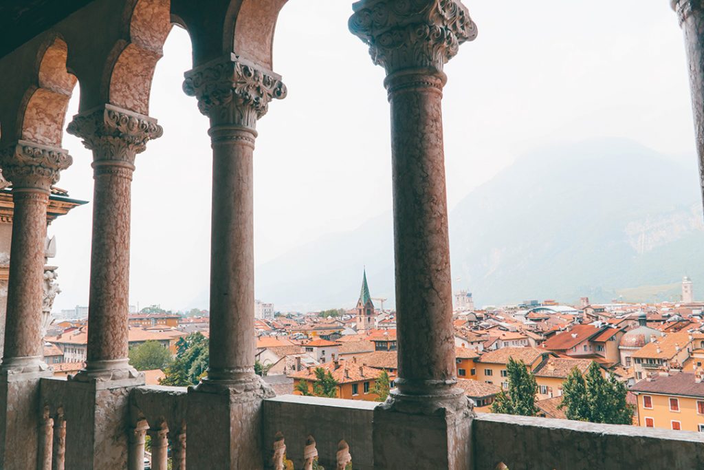 columns in the foreground looking out over a city of red roofs - one of the many places you can visit in Trentino