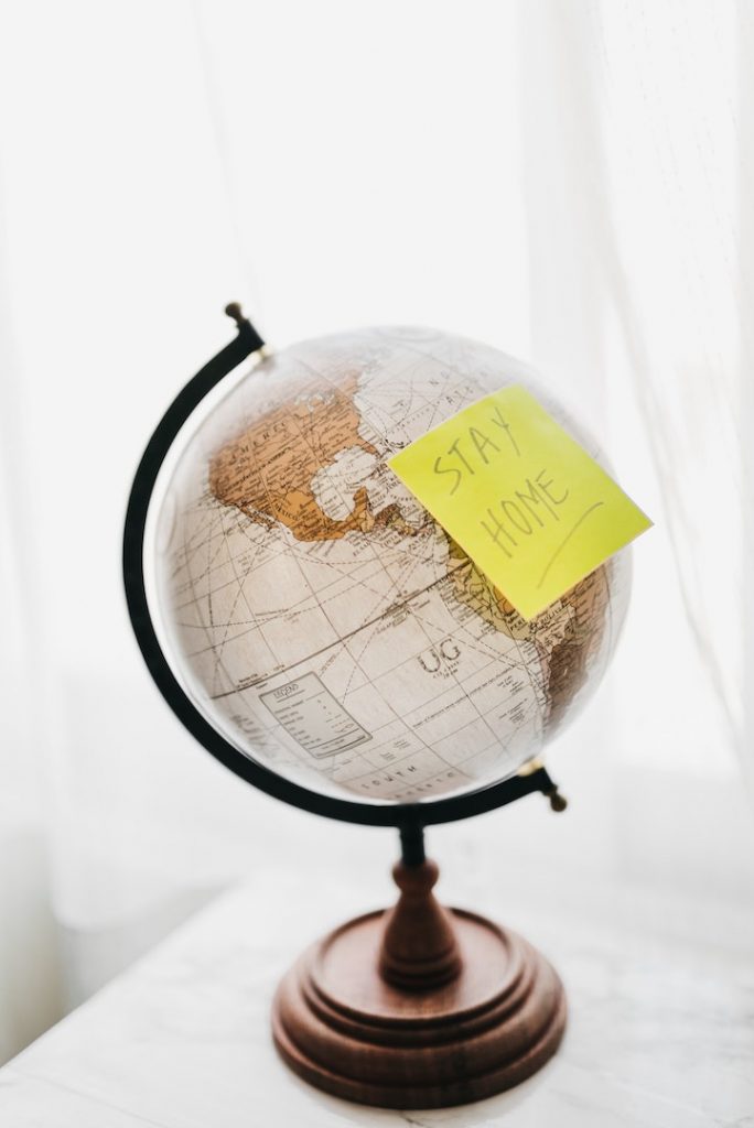 a globe with a sticky note that says "stay home" on it