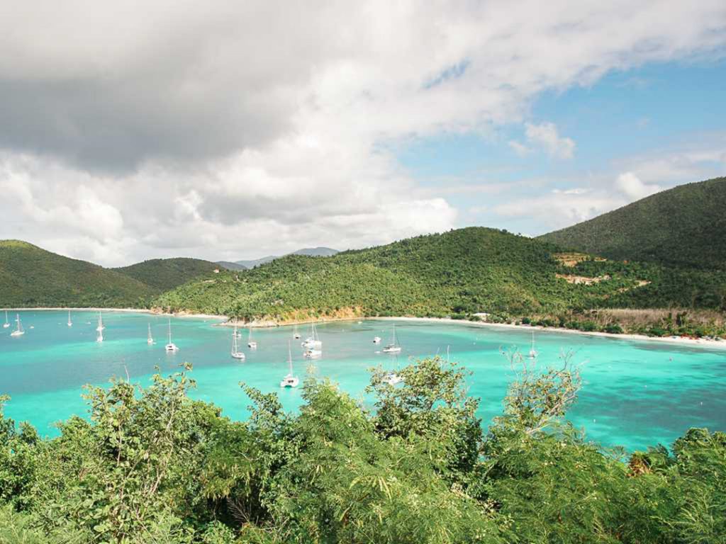 a bright blue ocean with green mountains in the background