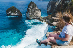 addie sitting on a cliff looking out at diamond beach on nusa penida