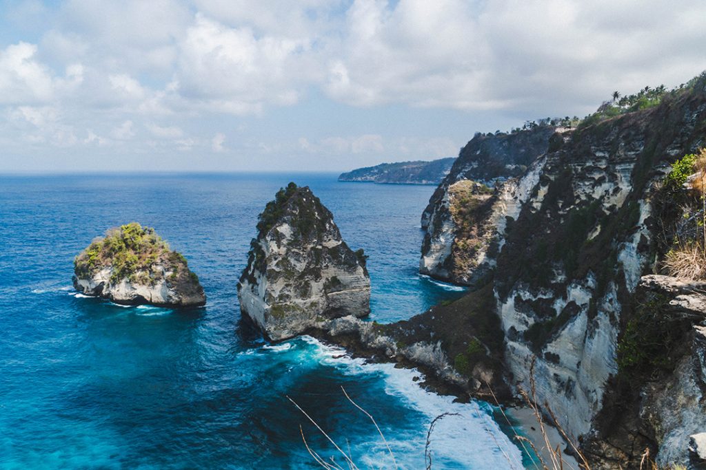 rocky cliffs jutting up from the ocean at diamond beach on nusa penida - nusa islands guide
