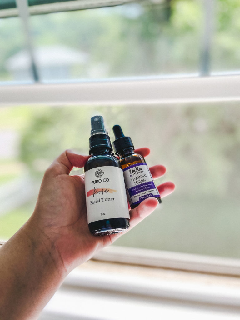 two small glass skincare bottles being held up by a hand