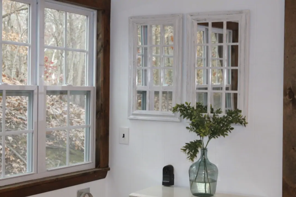 a large vase with stalks of leaves in it next to a window