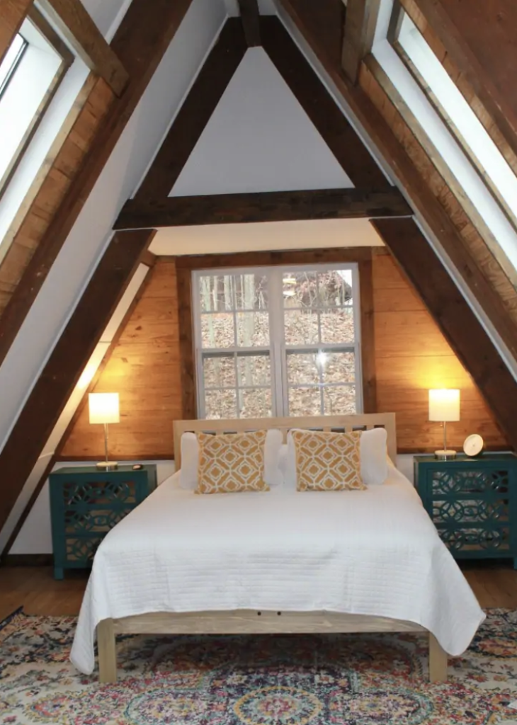 a white bed under a triangular vaulted ceiling