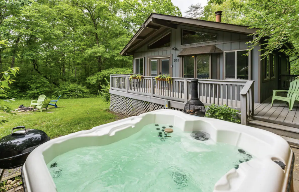 a hot tub in front of a small, dark dusty blue house