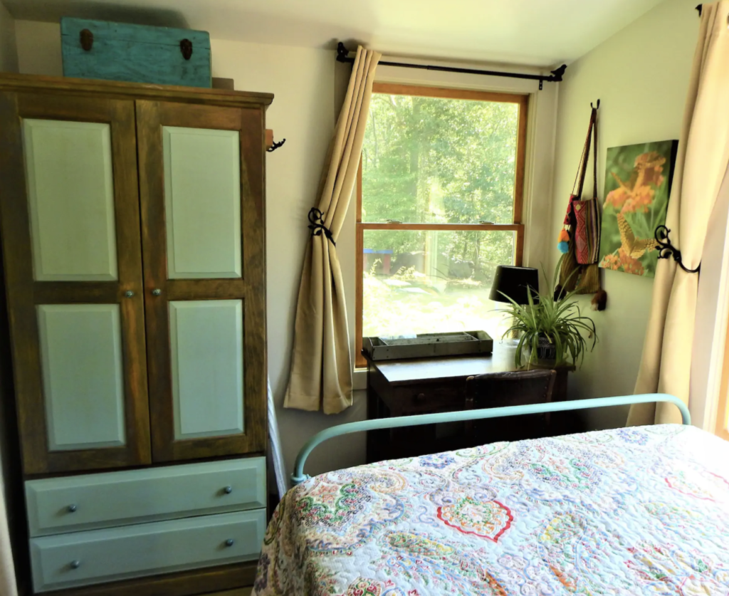 a bed with a quilt on it and a turquoise wardrobe
